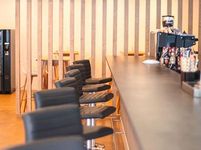 Bar dell'hotel moderna con alti sgabelli neri e rivestimento in legno sullo sfondo.