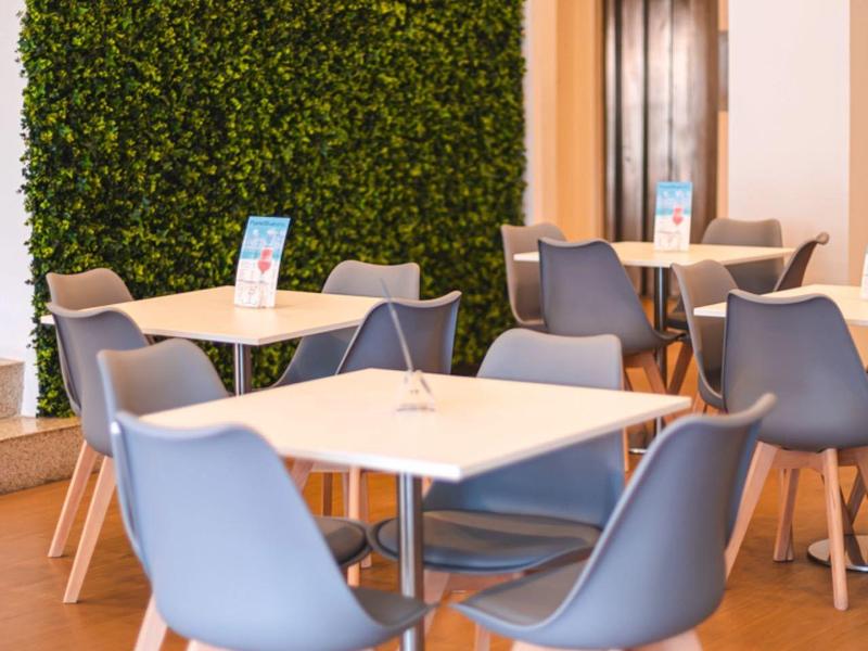 Nowoczesny kącik do siedzenia z szarymi krzesłami i zieloną ścianą roślinną w lobby hotelu.