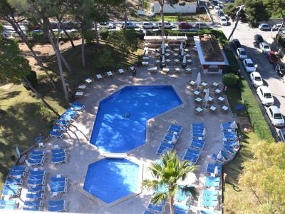 Strefa basenowa na zewnątrz z dwoma połączonymi basenami otoczonymi leżakami i parasolami.