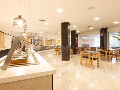 Salle à manger lumineuse avec buffet et plusieurs tables et chaises en bois.