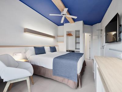 Chambre d'hôtel moderne avec accent de plafond bleu, lit double et fauteuil confortable.