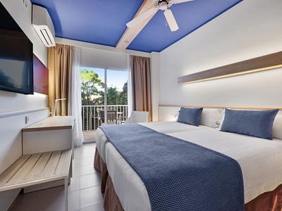 Chambre d'hôtel moderne avec lit double, décoration de plafond bleue et balcon avec vue.