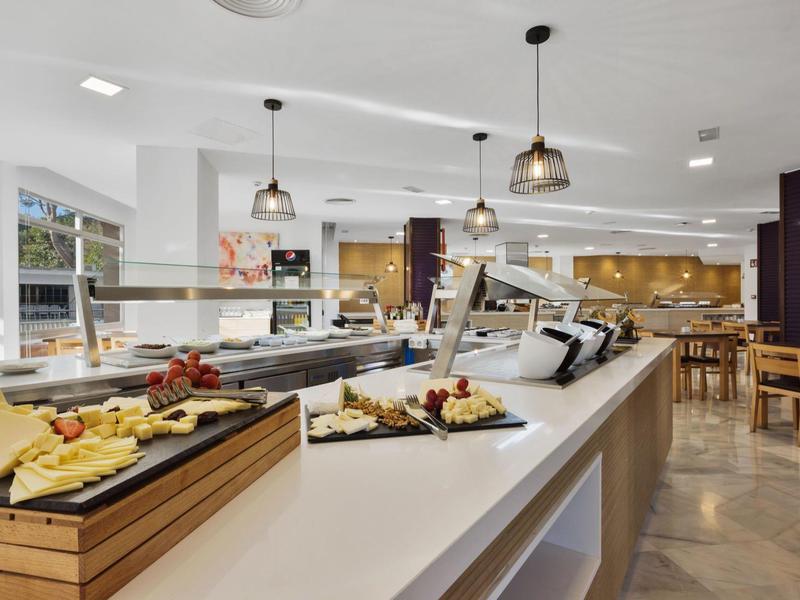 Espace petit-déjeuner moderne avec buffet de fromages variés dans un cadre lumineux d'hôtel.