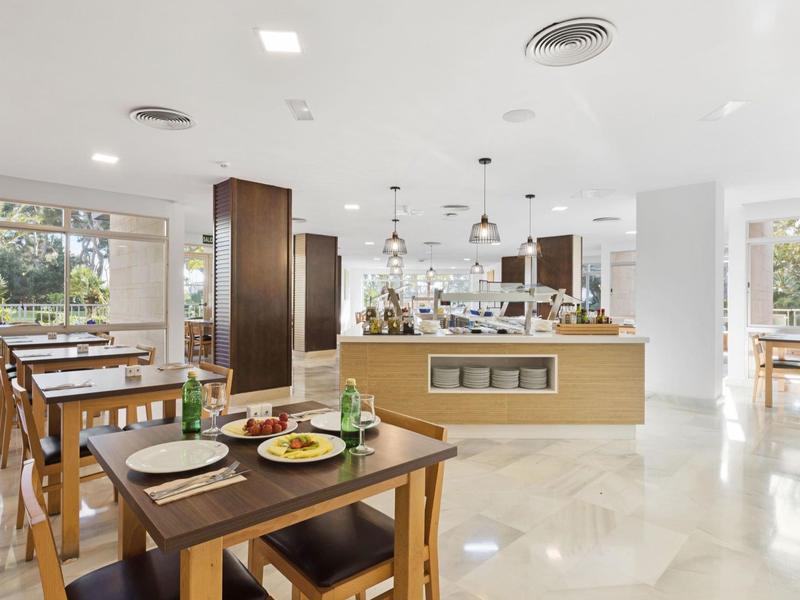 Restaurant lumineux avec mobilier en bois et espace buffet au design moderne.