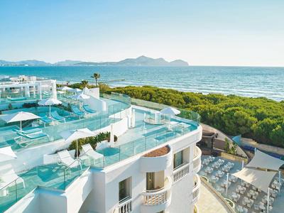 Hotel de lujo con terraza piscina y vistas al mar en un paisaje soleado.