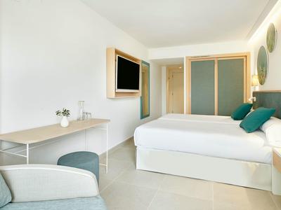 Camera d'hotel luminosa con letto matrimoniale, scrivania, sedia e TV a parete.