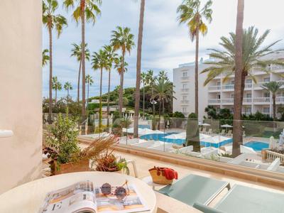 Vista sulla piscina dell'hotel con palme e sdraio in una giornata di sole.