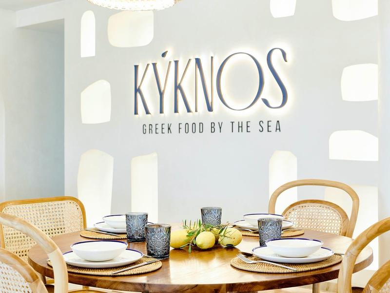 Interno elegante del ristorante con sedie in legno e tavolo apparecchiato da KYKNOS.