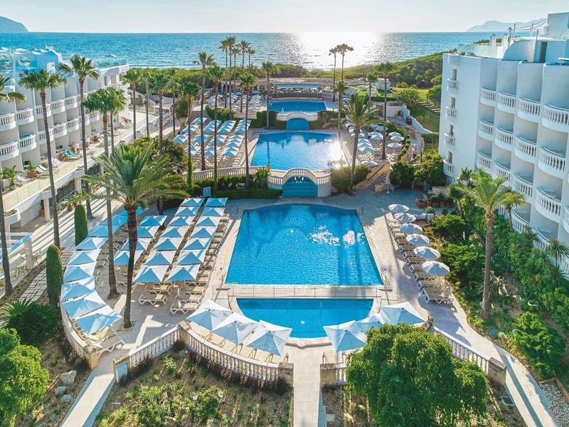Piscina dell'hotel con sedie a sdraio e palme vicino al mare soleggiato