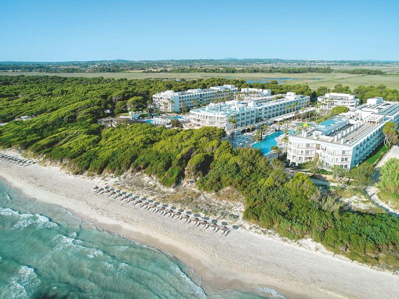 Vista aerea di un hotel sulla spiaggia con lettini e folta vegetazione sullo sfondo