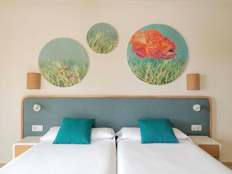 Camera doppia moderna con testiera blu e tre immagini rotonde di natura sopra il letto.