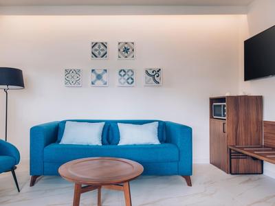 Modernes Wohnzimmer mit blauem Sofa, runden Holztisch, Stehlampe und Wandbildern in Pastellfarben.
