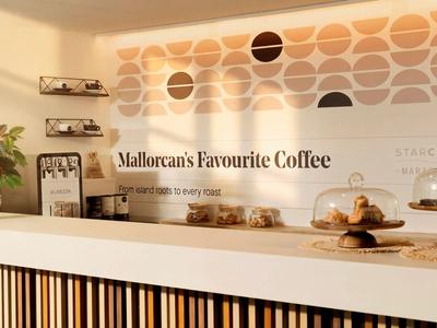 Area caffè moderna con pareti chiare, piante e offerte di caffè.