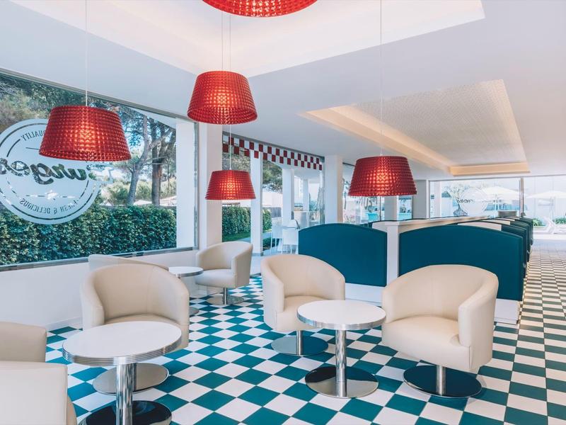 Moderna sala de hotel con sillones cómodos, separadores azules y suelo de baldosas blanco y negro.