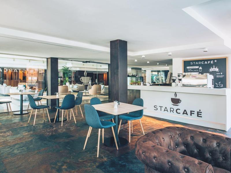 Café moderno con sillas azules, mesas blancas y un mostrador de recepción en el hotel.