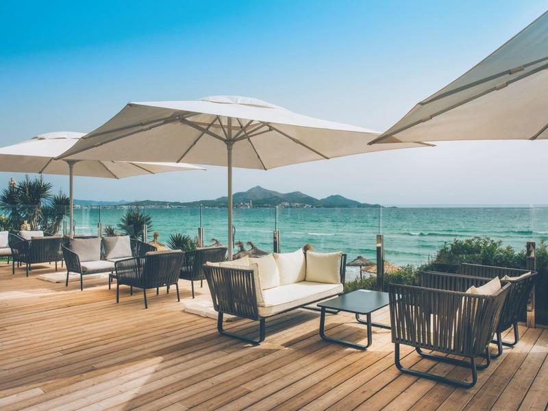 Asientos con sombrillas en una terraza de madera con vista al mar en un día soleado