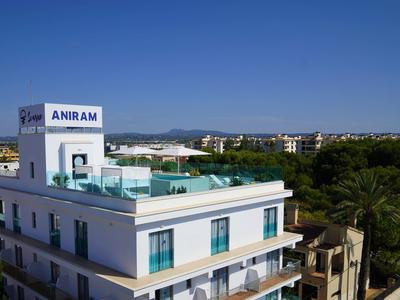 Edificio moderno de hotel con piscina en la azotea y cielo azul despejado de fondo.