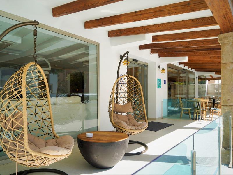 Terraza con dos sillones colgantes de ratán y vigas de madera en un hotel.