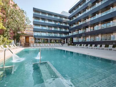 Piscina moderna de hotel con tumbonas y barandilla de cristal en un día soleado.