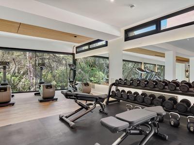 Palestra moderna con manubri, panche da allenamento e vista su alberi verdi