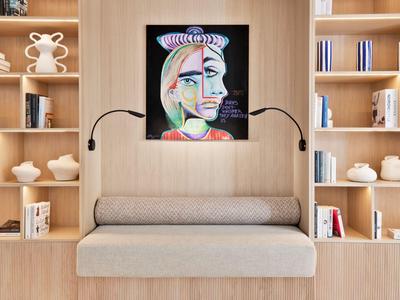 Area salotto moderna con libreria integrata e dipinto astratto colorato sulla parete.