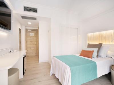 Habitación de hotel luminosa con cama doble, diseño moderno y suelo de madera.