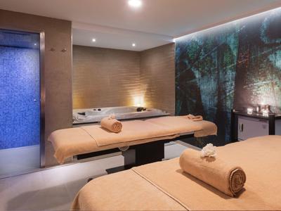 Moderní wellness místnost se dvěma masážními stoly a atmosférickým osvětlením.