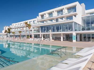 Moderní hotel s velkým venkovním bazénem, lehátky a oblastí ozdobenou palmami.