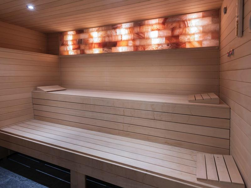 Interiér dřevěné sauny s vícestupňovými lavicemi a teplým osvětlením.
