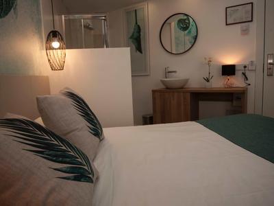 Przytulny pokój hotelowy z dwoma łóżkami, stylowymi poduszkami i pośrednim oświetleniem.