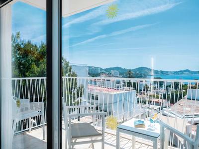 Balkon mit weißen Stühlen und Tischen mit Blick auf das Meer und die Berge.