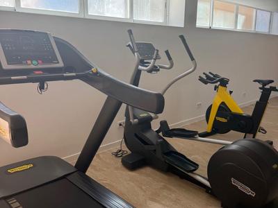 Interior view of a modern gym with a treadmill and stationary bikes.