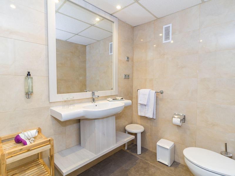 Jasna łazienka z umywalką, lustrem, ręcznikami i toaletą.