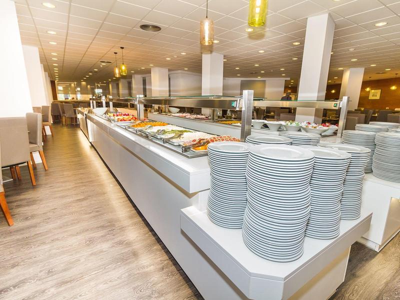 Strefa bufetu w restauracji z ułożonymi talerzami i różnymi potrawami.