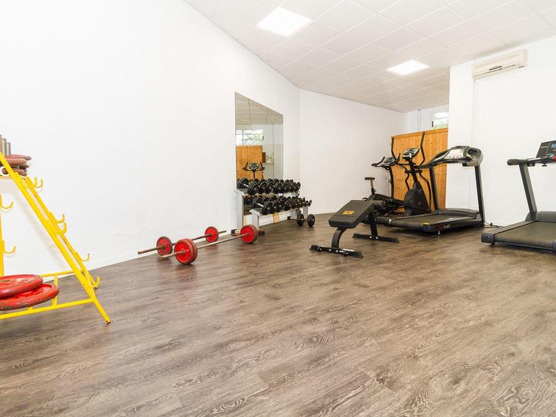 Jasna, nowoczesna siłownia z bieżnią, ławką do ćwiczeń i sprzętem fitness.