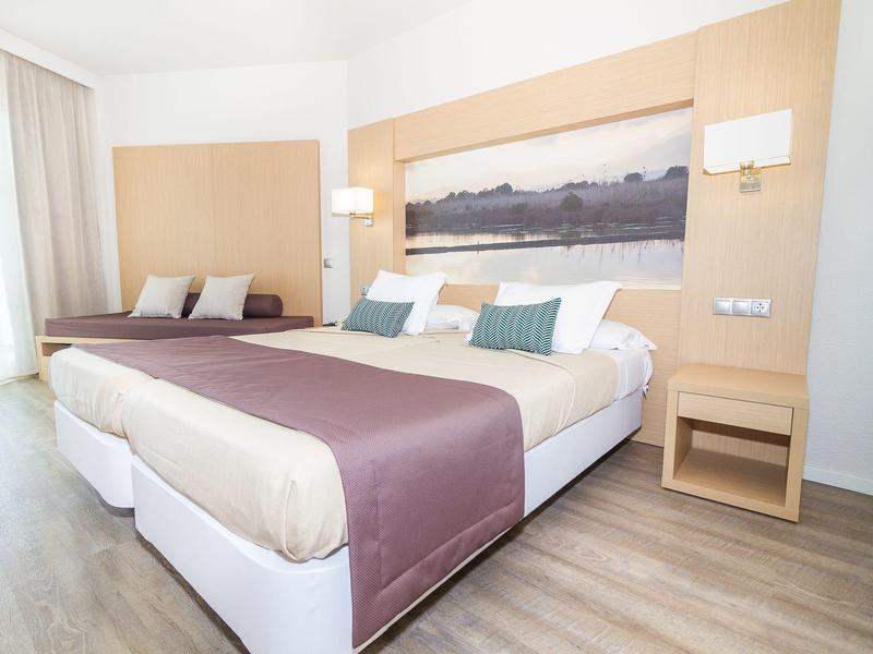 Nowoczesny pokój hotelowy z dwoma łóżkami, drewnianą podłogą i prostym wystrojem.