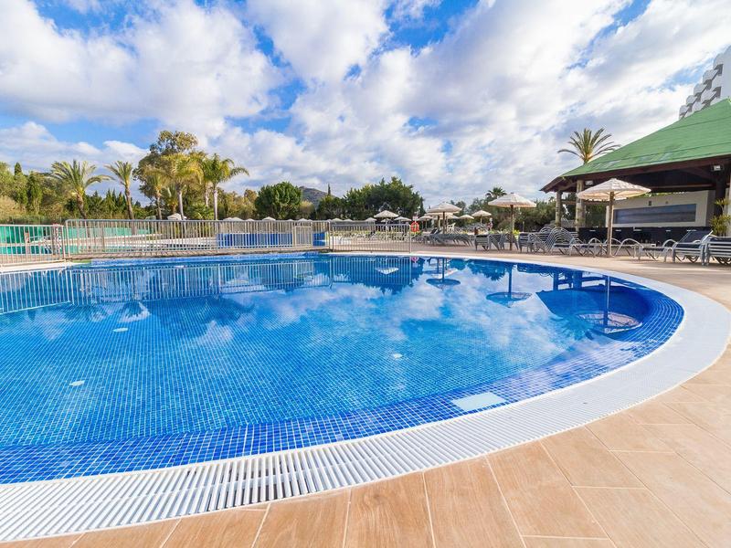 Duży, czysty basen na zewnątrz z parasolami i leżakami w hotelu.