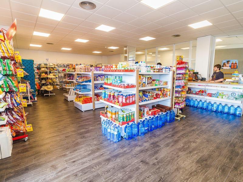 Wnętrze dobrze oświetlonego sklepu z półkami pełnymi artykułów spożywczych i butelkowanej wody.