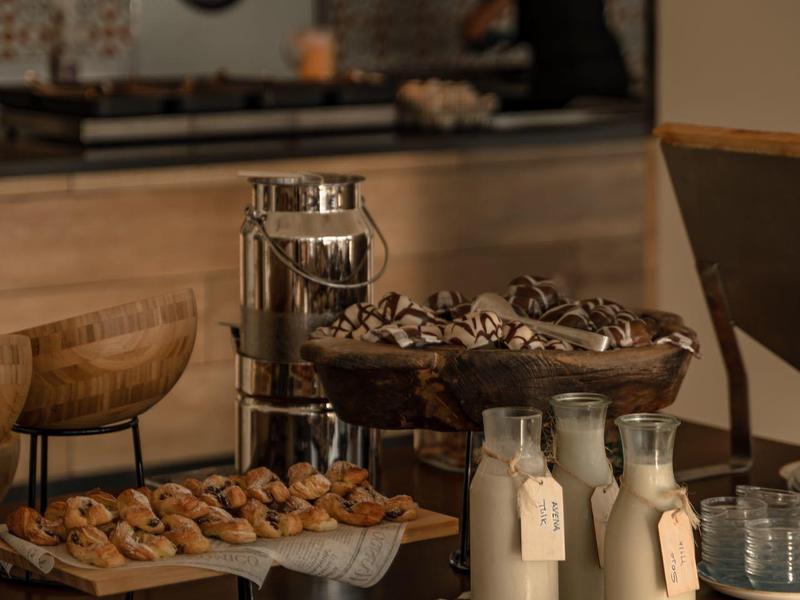 Tavolo rustico per la colazione con noci, bottiglie di latte e ciotole davanti alla cucina