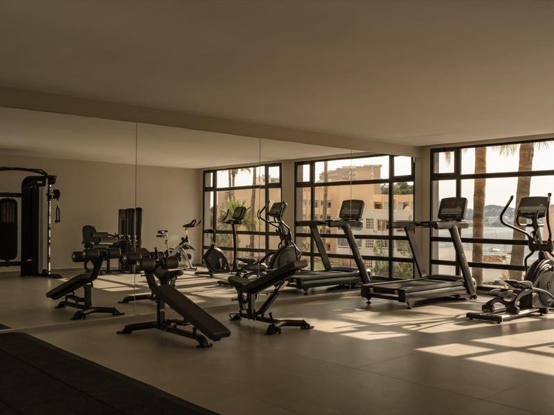 Palestra luminosa con attrezzature moderne e grandi finestre.