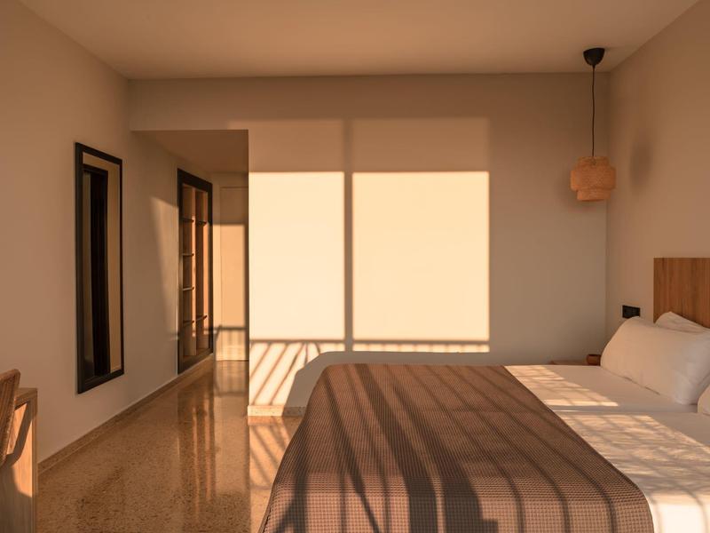 Camera d'hotel moderna con letto matrimoniale, mobili in legno e balcone soleggiato