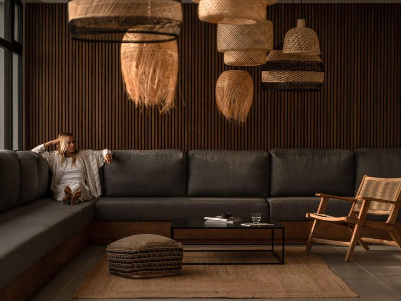 Soggiorno accogliente con grandi divani in pelle, sedia in legno e varie lampade intrecciate.