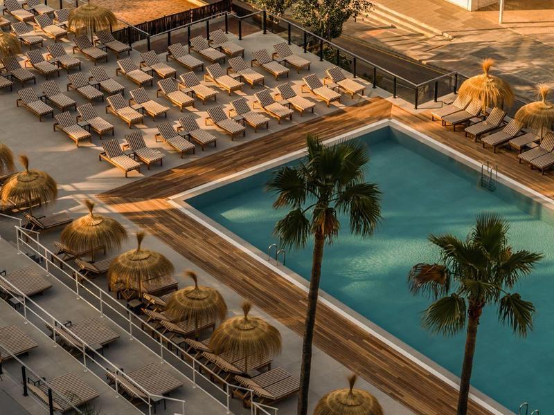 Grande piscina con molte sdraio e ombrelloni in un resort alberghiero.