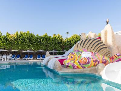 Piscine pour enfants avec un toboggan aquatique en forme de poisson coloré et des chaises longues en arrière-plan.