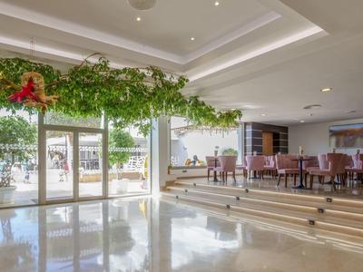 Salle à manger lumineuse avec des marches, des plantes vertes au plafond et accès à la terrasse avec vue sur la plage.