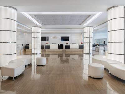 Hall d'hôtel moderne avec sièges blancs et colonnes illuminées sur sol brillant