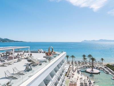 Hôtel avec terrasse sur le toit, piscine et vue sur la mer par une journée ensoleillée.