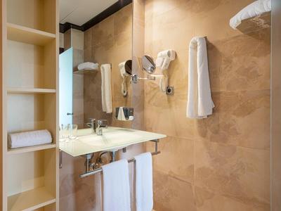 Salle de bain moderne avec lavabo beige et serviettes accrochées au mur.
