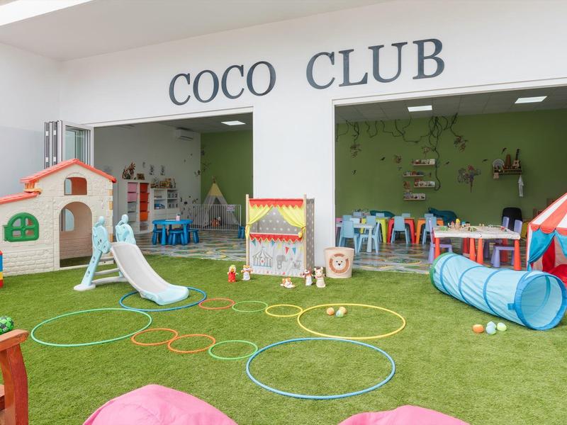 Aire de jeux pour enfants avec structures d'escalade, tunnel, toboggan et jouets colorés dans un hôtel.