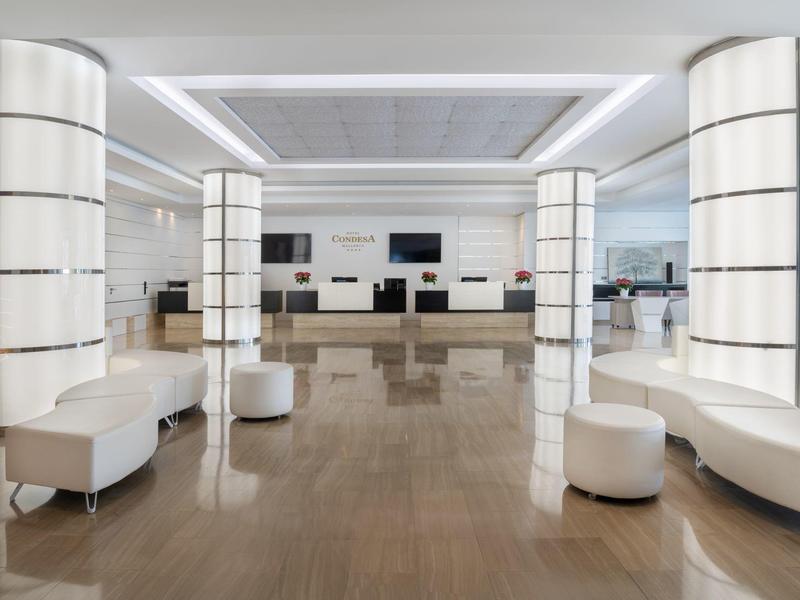 Hall d'hôtel moderne avec sièges blancs et colonnes illuminées sur sol brillant